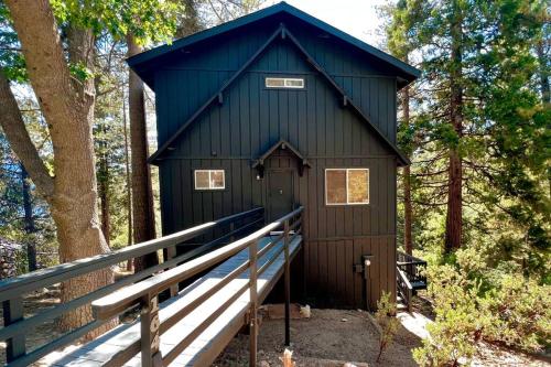a black building in the middle of a forest at Glimmer Chalet Treetop A-frame cabin lake view in Lake Arrowhead