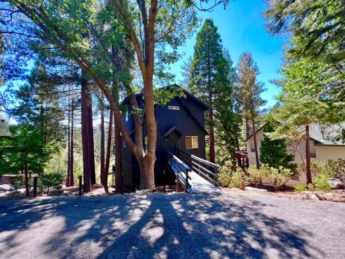 a black house in the middle of a forest at Glimmer Chalet Treetop A-frame cabin lake view in Lake Arrowhead