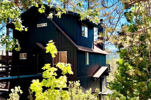 a black house with a gambrel roof at Glimmer Chalet Treetop A-frame cabin lake view in Lake Arrowhead