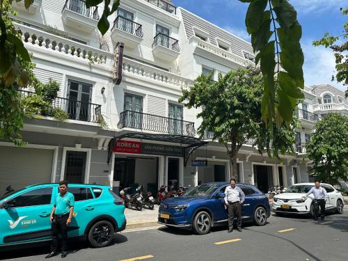Korean Hotel Resort في Tây Ninh: رجلين واقفين بجانب السيارات في شارع المدينة