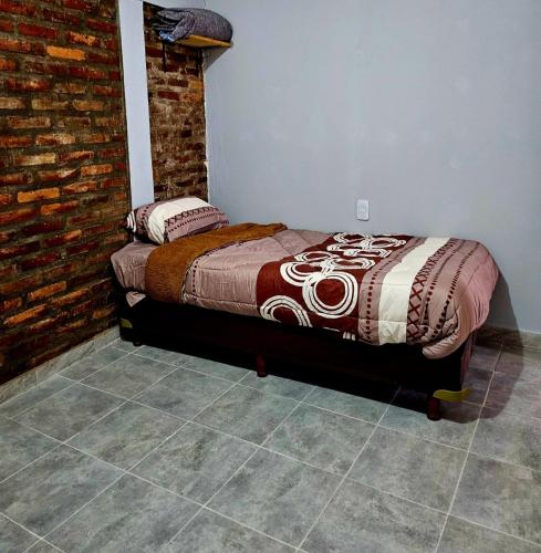 Cama en habitación con pared de ladrillo en El gumer en San Fernando del Valle de Catamarca
