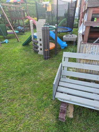 Un banco sentado en el césped junto a un parque infantil. en Makowe Domki, en Władysławowo