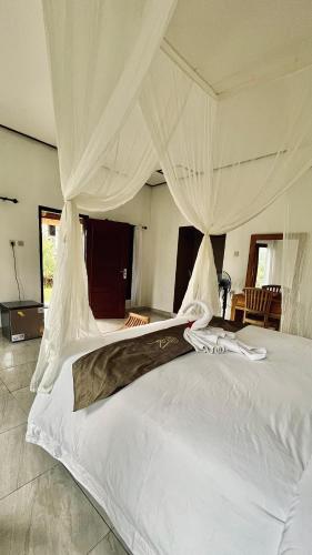 um quarto com uma grande cama branca com cortinas em Papahan Bali em Sidemen