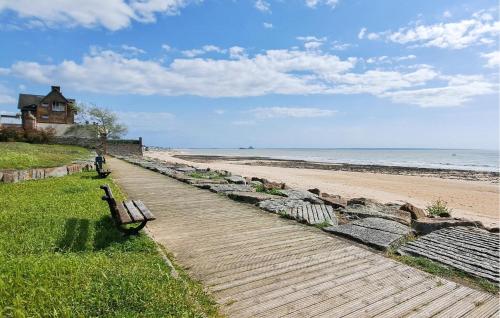 un chemin en bois menant à une plage avec un banc dans l'établissement Cozy Home In Sartilly-Baie-Bocage, à Angey