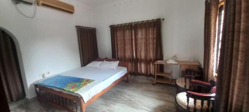 a bedroom with a bed and a desk and a chair at Green Heaven Kumarakom in Kumarakom