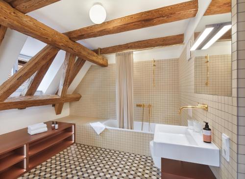 a bathroom with a white sink and a tub at Engelwirt Hotel & Apartments in Berching
