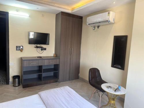 a room with a bed and a television and a chair at Hotel Kritika in Greater Noida