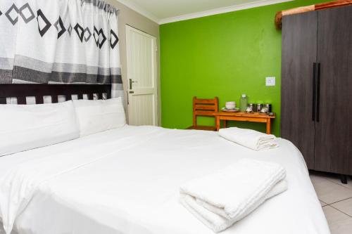 a bedroom with a white bed and a green wall at Botanik Inn in Pretoria