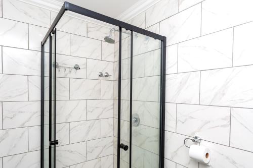 a shower with a glass door in a bathroom at Botanik Inn in Pretoria