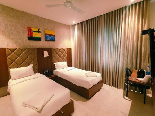 a hotel room with two beds and a phone at Hotel Kunal Palace in Ahmadnagar