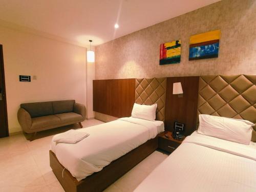a hotel room with two beds and a chair at Hotel Kunal Palace in Ahmadnagar
