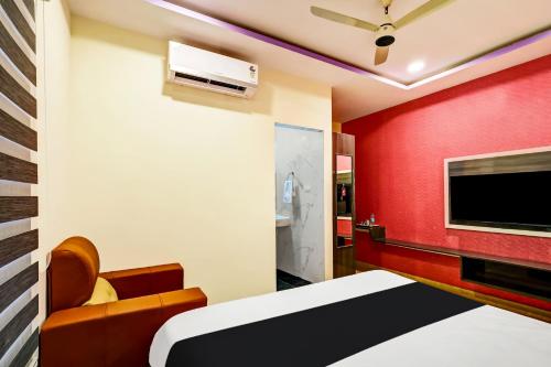 1 dormitorio con pared roja, cama y TV en OYO AADYA INN, en Tirupati