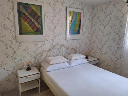 a bedroom with a white bed with two night stands and paintings at Apartment Srsen in Kučište