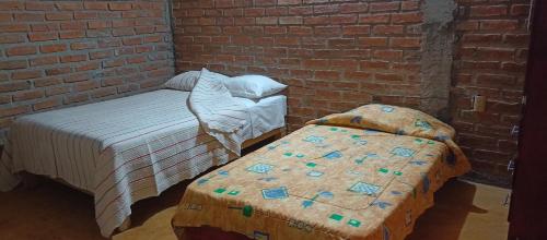 a room with two beds and a brick wall at Villas Carmelita hostal in Paso de las Palmas