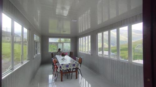 a dining room with a table and chairs and windows at Zaur Guest hause in Xınalıq