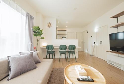 a living room with a couch and a table and chairs at Furano Ezo Murasaki B in Furano