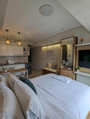 a large white bed in a room with a kitchen at Joyce Condo @ Centrio Towers in Cagayan de Oro