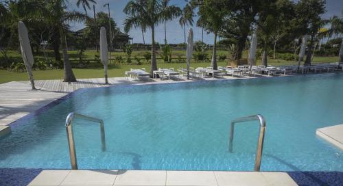 a large swimming pool with chairs and palm trees at Radisson Blu Hotel & Residence Maputo in Maputo