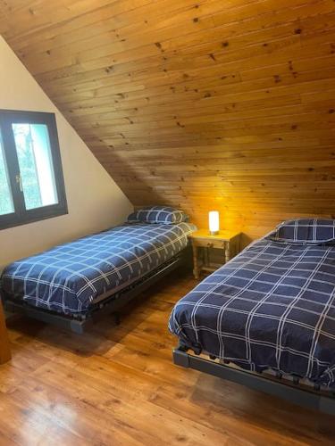deux lits dans une chambre avec un plafond en bois dans l'établissement Gîte Les Reculons au pied du lac, à Les Midoux