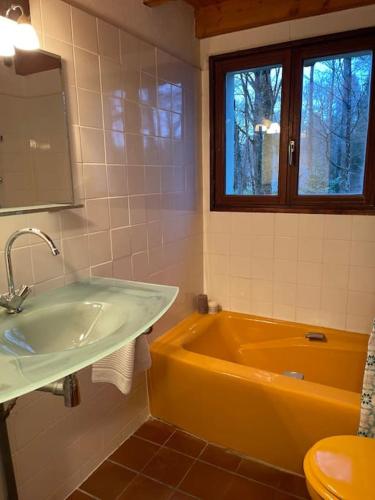 La salle de bains est pourvue d'une baignoire jaune et d'un lavabo. dans l'établissement Gîte Les Reculons au pied du lac, à Les Midoux