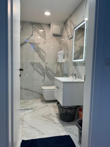 a bathroom with a white sink and a mirror at Suite Rana Hedhun in Shëngjin