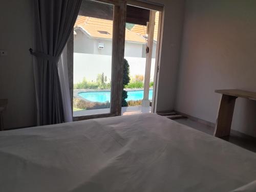 a bedroom with a bed and a view of a pool at Maha Rama Villas Amed in Amed