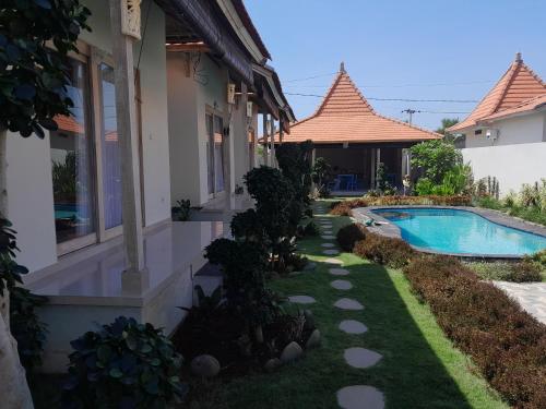 a backyard with a swimming pool and a house at Maha Rama Villas Amed in Amed