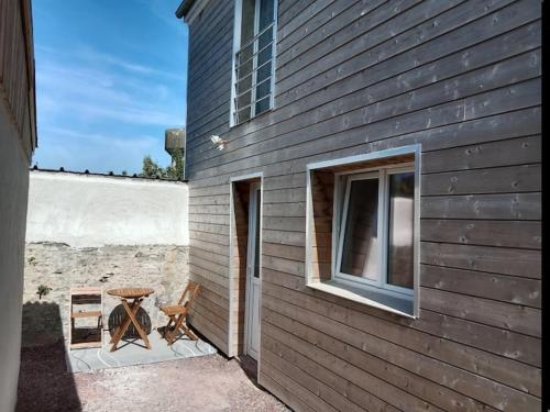 a table and a chair sitting next to a building at Poisson in Isigny-sur-Mer
