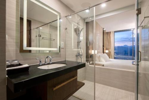 a bathroom with a sink and a shower and a bed at Panorama Nha Trang Condotel by One in Nha Trang