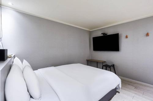a bedroom with a white bed and a flat screen tv at Yam hotel in Guri