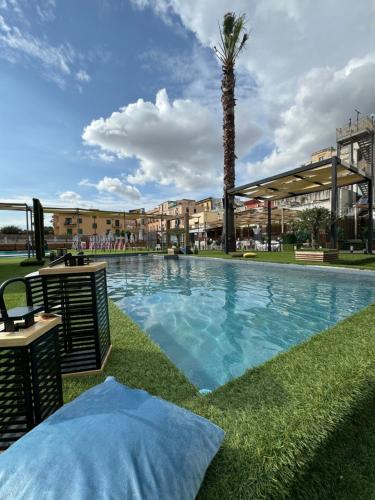 ein großer Pool mit einer Palme neben einem Gebäude in der Unterkunft Hotel Borbonico di Pietrarsa in Portici