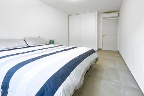 - une chambre blanche avec un lit bleu et blanc dans l'établissement Magnifique T3, à Bastelicaccia
