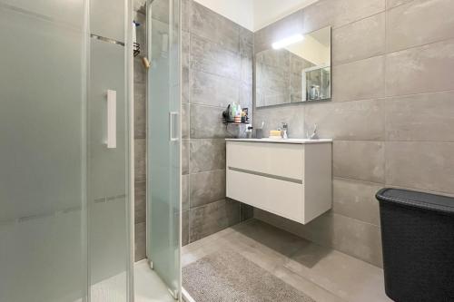 La salle de bains est pourvue d'un lavabo blanc et d'une douche. dans l'établissement Magnifique T3, à Bastelicaccia