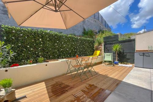 un patio avec un parasol, une table et des chaises dans l'établissement Magnifique T3, à Bastelicaccia