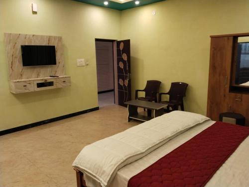 a bedroom with a bed and a flat screen tv at Red Stone Resort in Yercaud