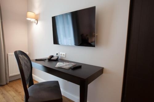 a desk with a television on a wall with a chair at Hotel Rheinischer Hof Bad Soden in Bad Soden am Taunus