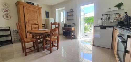 a kitchen with a wooden table and chairs and a table at Charmant appartement en Rez de jardin in Sartène