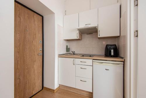 奈達的住宿－Studio Relax，厨房配有白色橱柜和木门。