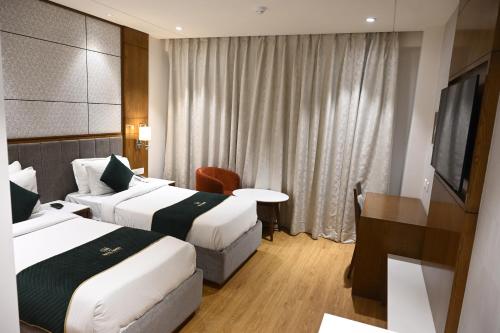 una camera d'albergo con due letti e una televisione di HOTEL RAMA CONTINENTAL a Prayagraj