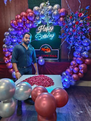 a man standing in front of a table with balloons at Mauji's Villa Hotel & Guest House in Prayagraj