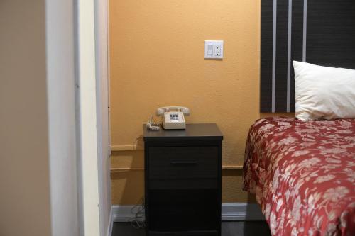 a room with a bed and a phone on a night stand at A-1 Budget Motel in Klamath Falls