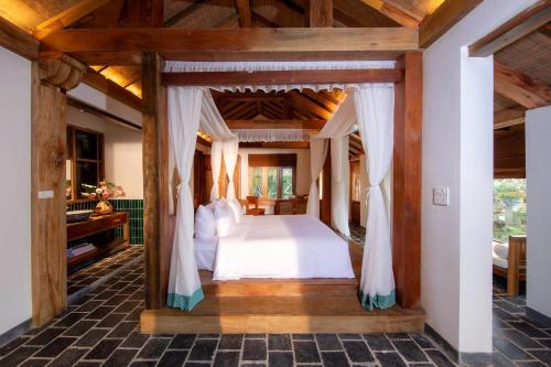 1 dormitorio con cama con dosel en una casa en Mua Caves Ecolodge (Hang Mua) en Ninh Binh