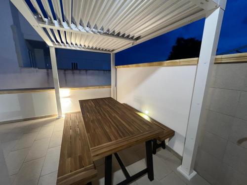 a wooden bench on a balcony with awning at OWNER ITALY - APARTMENT A in Torre San Giovanni Ugento
