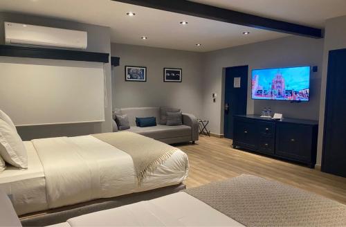 a bedroom with a bed and a couch and a flat screen tv at Hotel Verbena in San Miguel de Allende