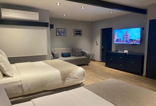 a bedroom with a bed and a couch and a flat screen tv at Hotel Verbena in San Miguel de Allende