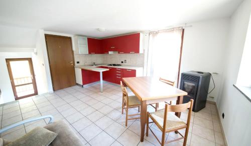 uma cozinha com armários vermelhos, uma mesa e cadeiras em la maison jaune em Aosta