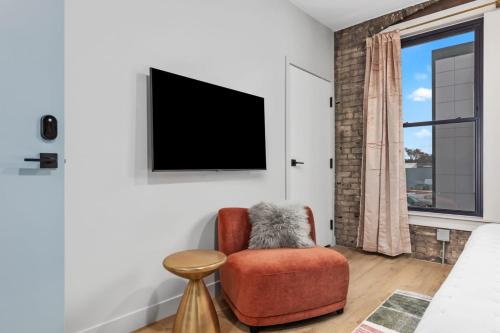 a living room with a chair and a flat screen tv at BlueJay Hotel in Grand Rapids