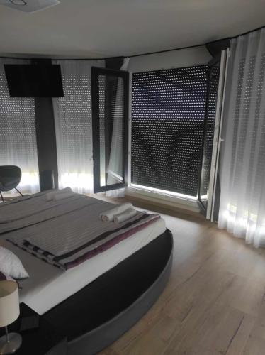 a bedroom with a bed and a large window at WEST Panorama Penthouse - apartment with a fantastic view of the city in Szombathely