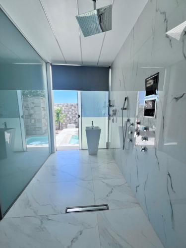 baño con suelo de mármol blanco y ventana grande en One Bedroom Pool House by Olivujoj, en Anavyssos