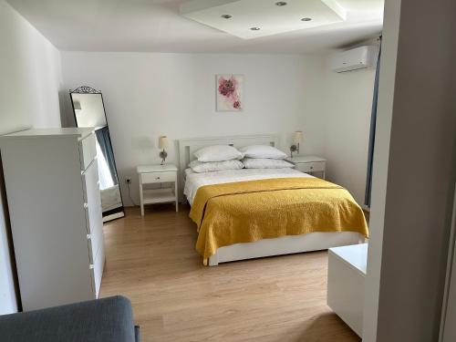 a bedroom with a bed with a yellow blanket at VOLMEfamily in Pula
